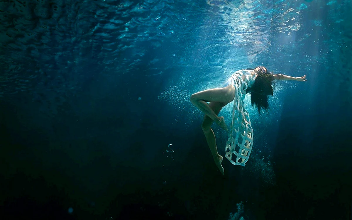 Девушка плавает в море под водой