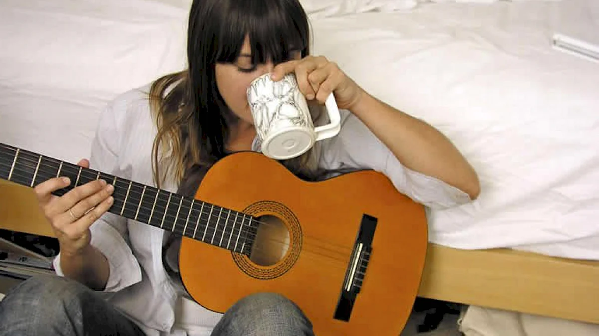 Девушка с гитарой на кровати
