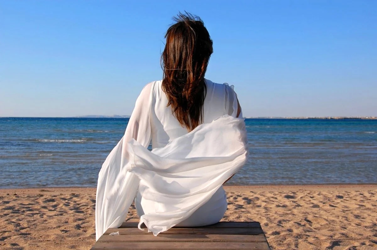 Девушка спиной на пляже в одежде